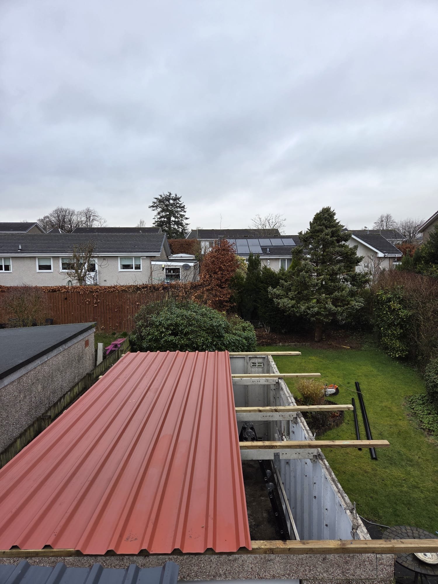 New red roof sheets being installed across the garage with the roof supports visible