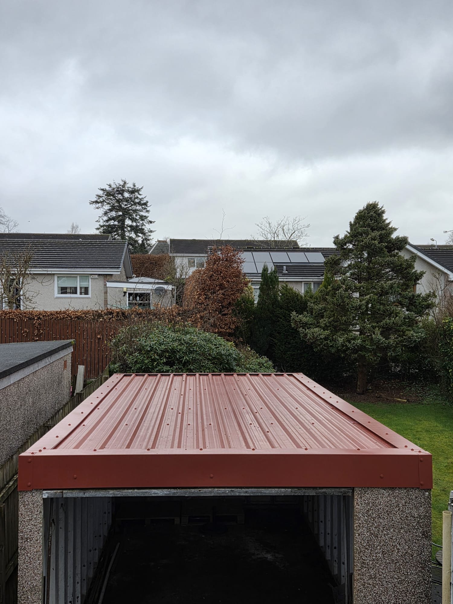 Completed red profiled garage roof with matching red edge trims