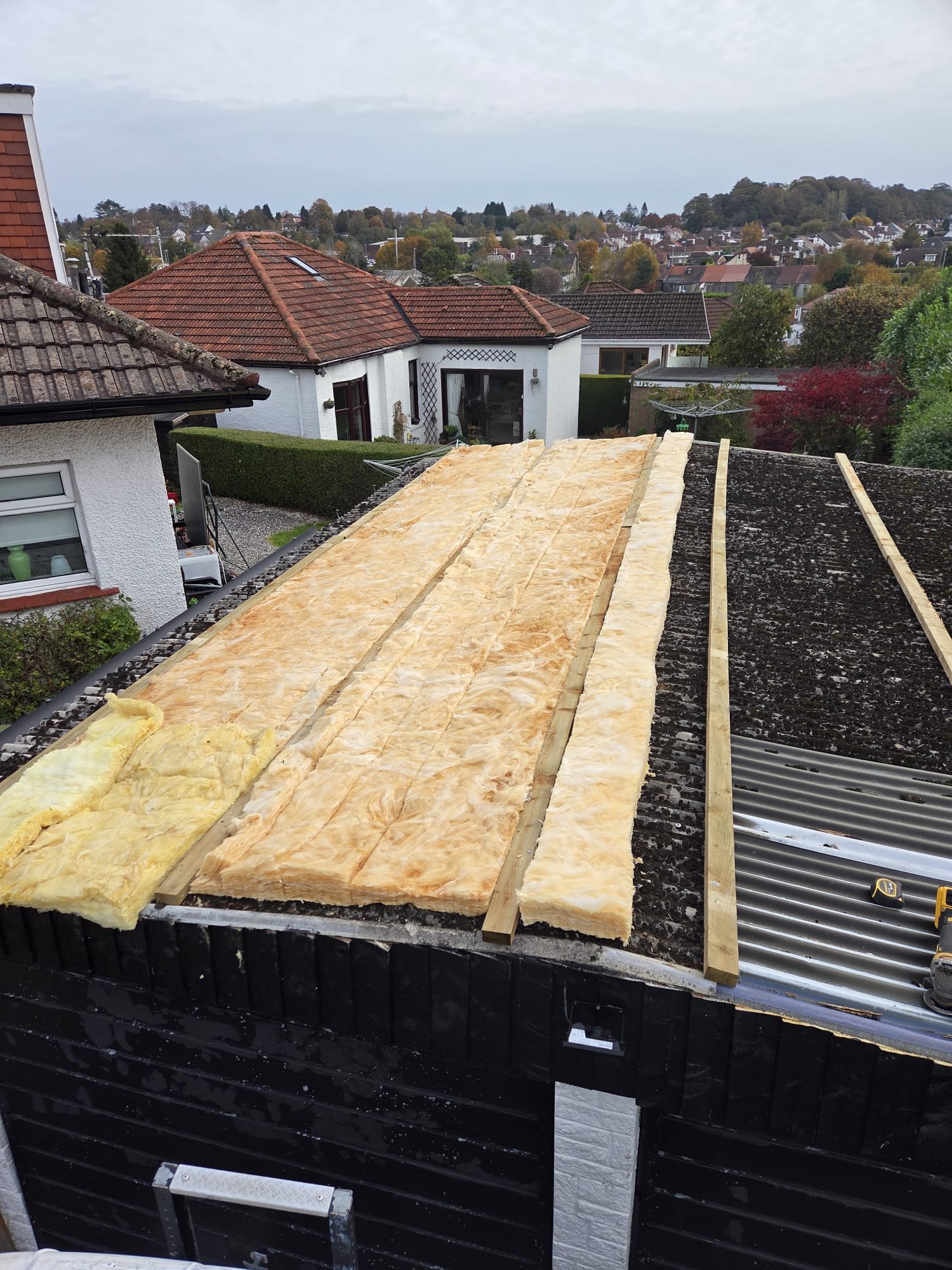 100mm cladding insulation being laid between timber battens over a garage roof