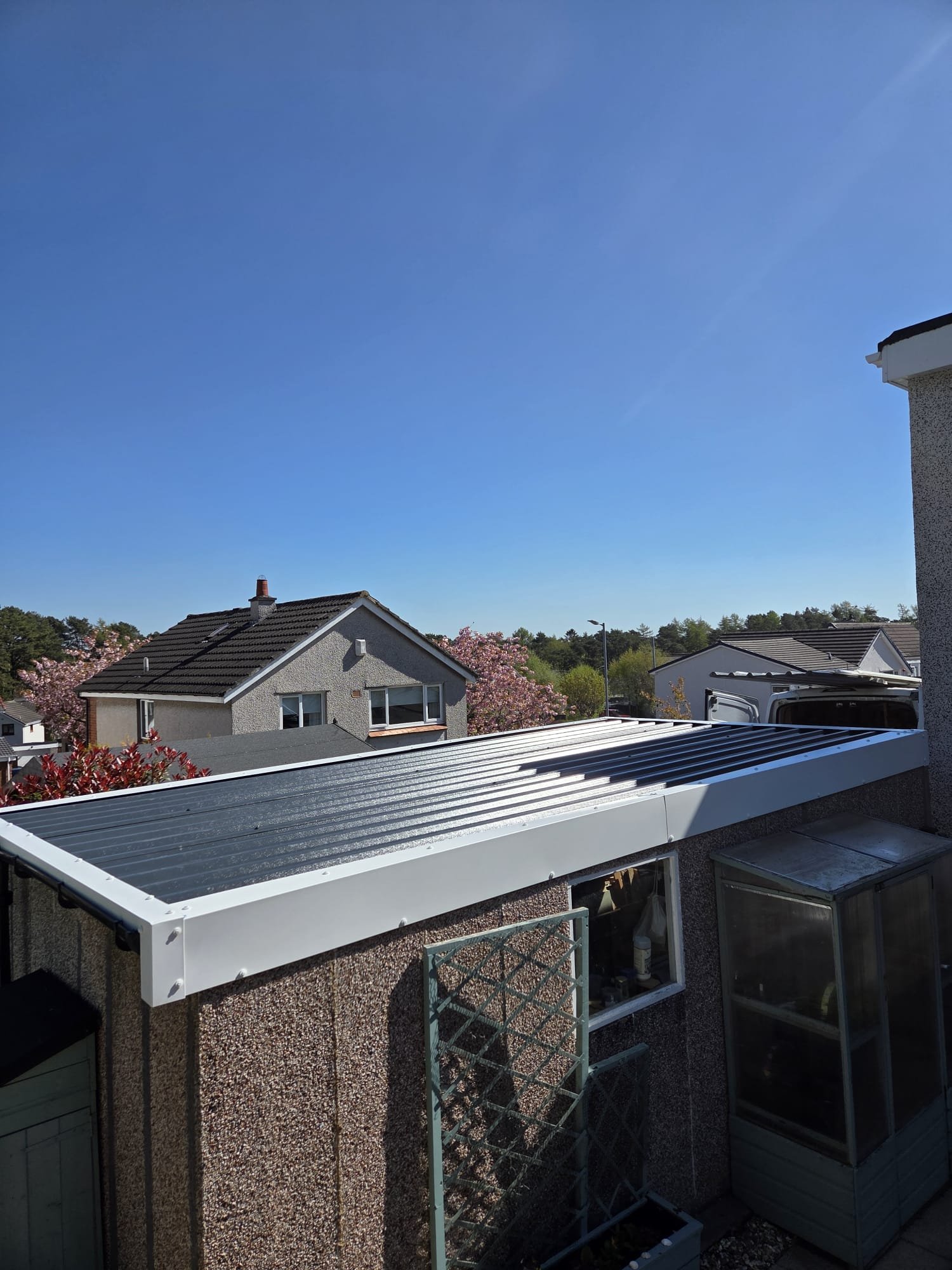 Completed grey profiled garage roof with white trims viewed from the side
